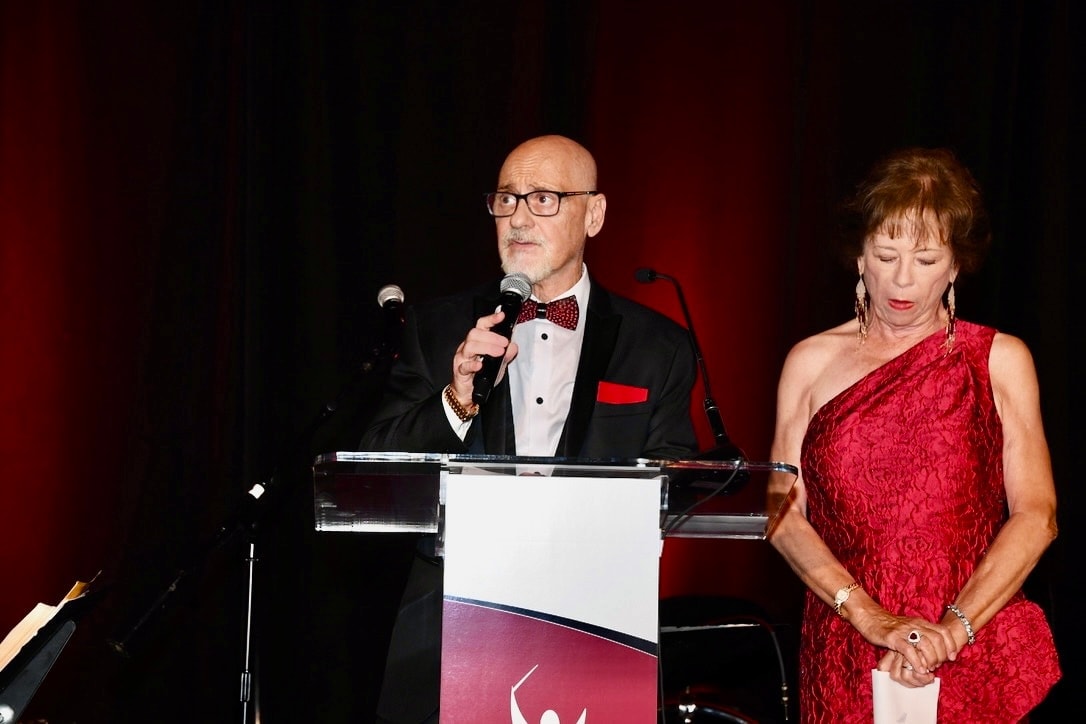 Rudy and Christina Andrea speaking at a formal gala event